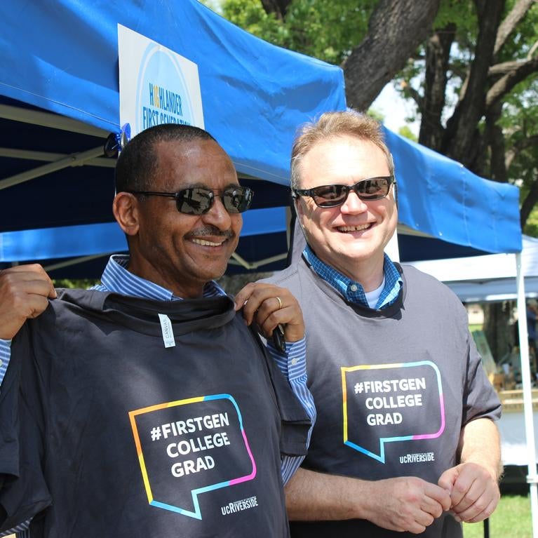Two first-generation faculty members holding t-shirts