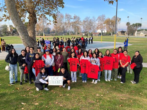 Group of UCR students, some holding red MLK t-shirts, in Bordwell Park