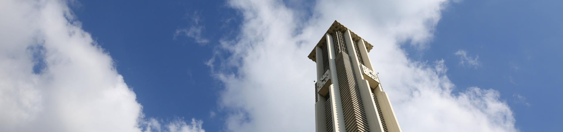 Looking up at the UCR Bell Tower against a blue sky with white clouds
