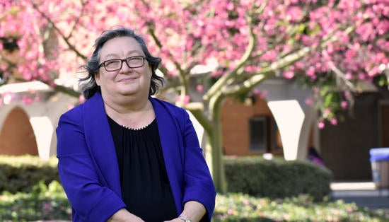 Provost Cynthia Larive, Pink Tree, cropped for teaser Provost Larive smiling in front of a pink tree